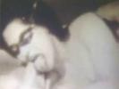 A woman who is wearing a mask is playing with a dildo on a bed when her husband comes in. A little later he is laying down and she is sucking his cock. She then lays down on her back so he can climb on top in order to fuck her.