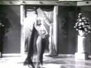 In this classic movie we see a performance by Faith Bacon, a stripper from yesteryear. She stands in the middle of a stage, hiding her nearly naked body from her audience with a veil. Then she dances about, gradually showing more and more skin.