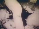 A blonde girl is sitting on the floor in between two naked guys. They play with her hairy pussy and she sucks their dicks in return. She lies down on the couch to have her pussy licked. Finally one of the guys fucks her deep in her mouth.