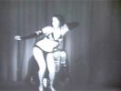 The famous stripper Kalantan is dancing on a stage, dressed in a black, exotic bikini and high heels. She sways her hips about, showing her slim body off to the camera.