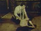 A man and a woman are on the floor of the living room. He is forcibly removing her clothes while she protests in a loud voice. When she is naked, the guy fucks her hard, folding her legs against her chest to penetrate her deeper.