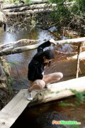 Teenage brunette peeing into a river in the park