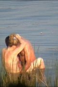 Tanned hung stud fucks a naked blonde in a lake