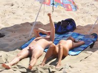 Nude teen friends play around at a public beach